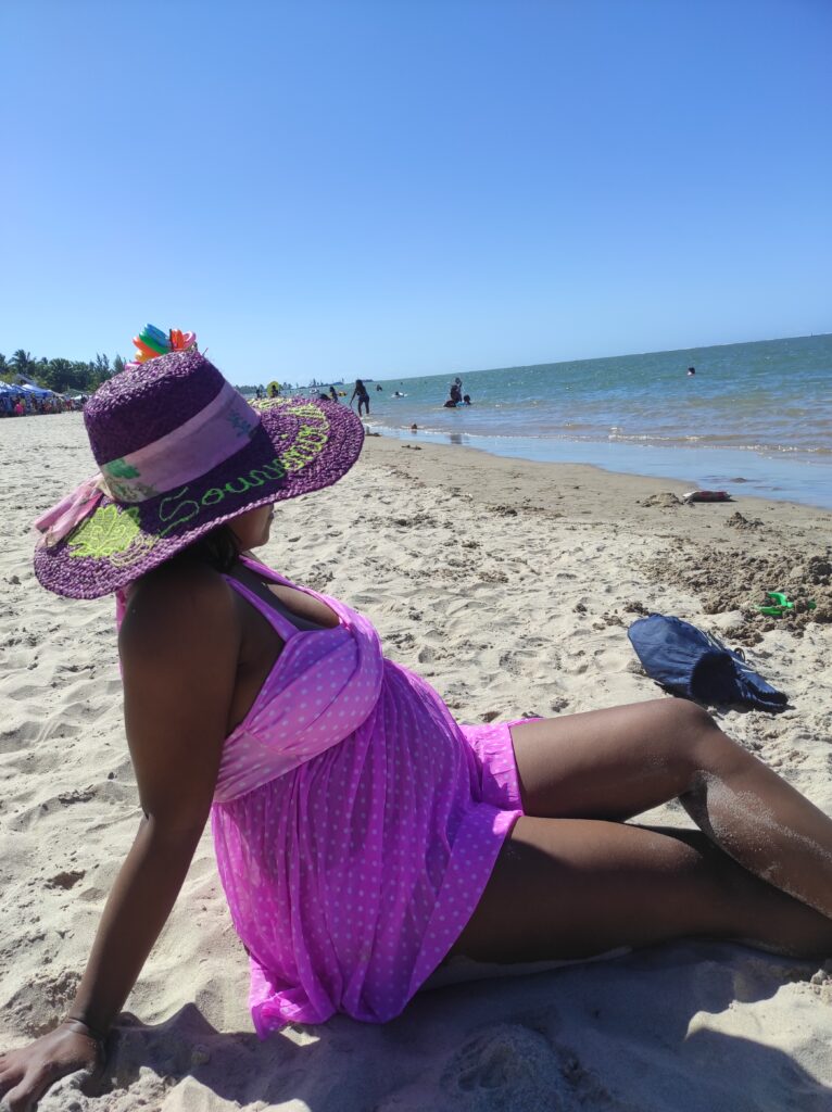 Une femme enceinte se relaxant sur la plage, appréciant le soleil.